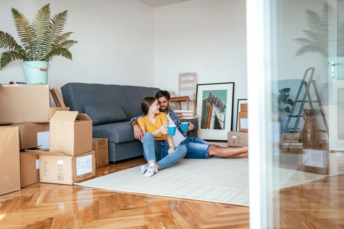 A man and woman sitting and smiling in their house